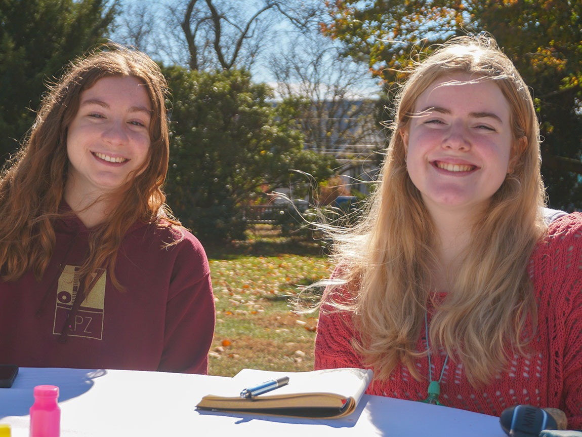 Two college students sit outside on a sunny day